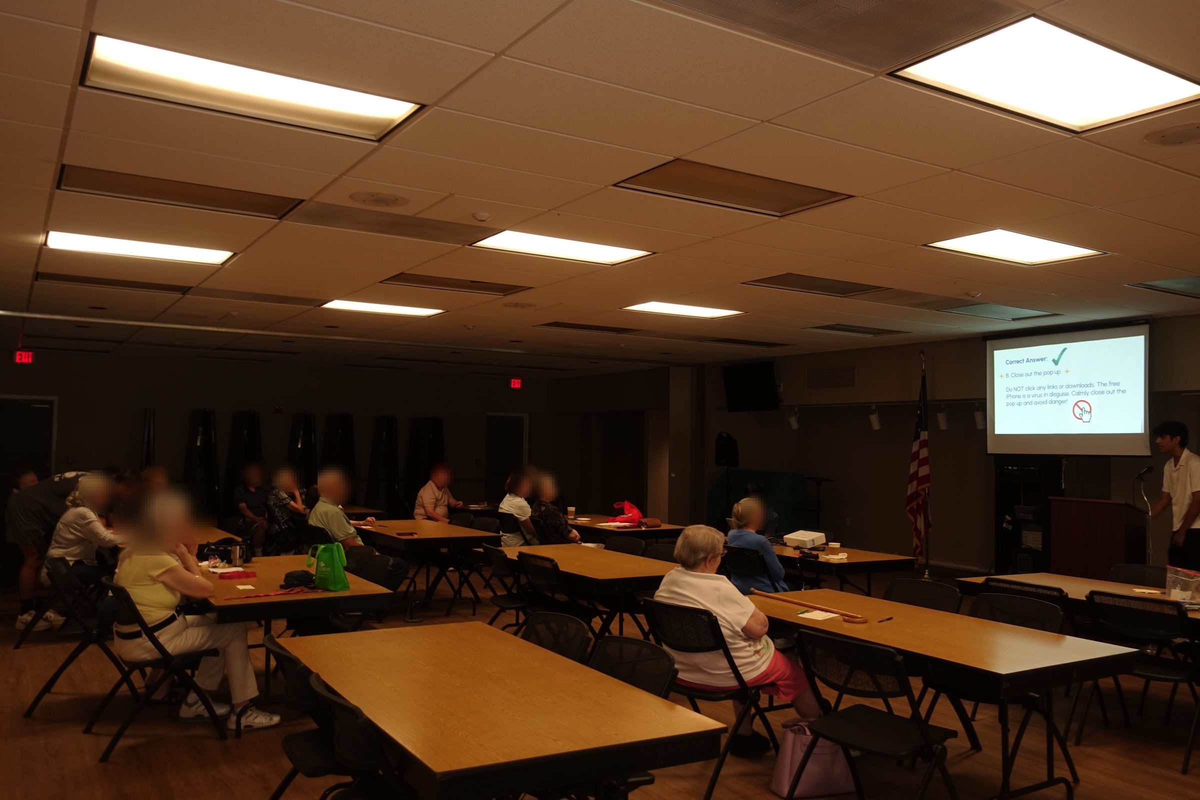 A room of older adults seated at tables, attending an in-person Unmasked session on spotting scams.